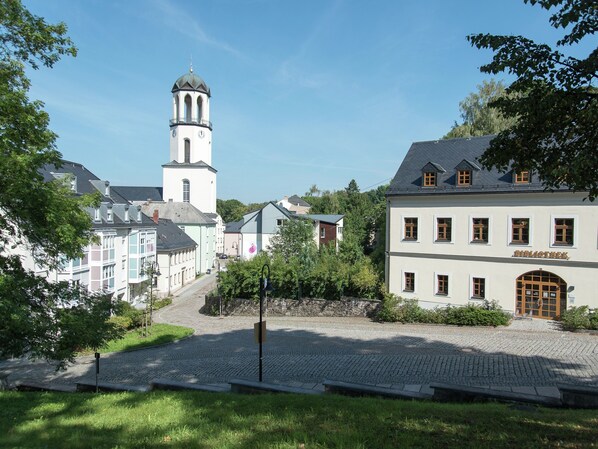 A town square with cobblestone pavement, a church tower, and buildings with traditional architecture.