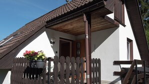 A traditional chalet with a sloped roof, wooden balcony, and a flower pot on the porch. - Holiday Home Beerheide Near Ski Slopes (Auerbach)