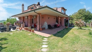 A two-story house with a covered patio, outdoor seating, and potted plants. - Villa in Monterotondo With Pool & Tiber Views (Monterotondo)