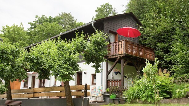 A two-story house with a balcony, surrounded by greenery. - Apartment Near Willingen & Winterberg Ski Slopes (Medebach)