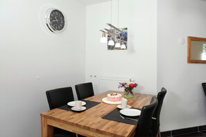 A dining area with a wooden table, black chairs, a cake, and a clock on the wall. - Holiday Home in Epen With Garden & BBQ (Epen)