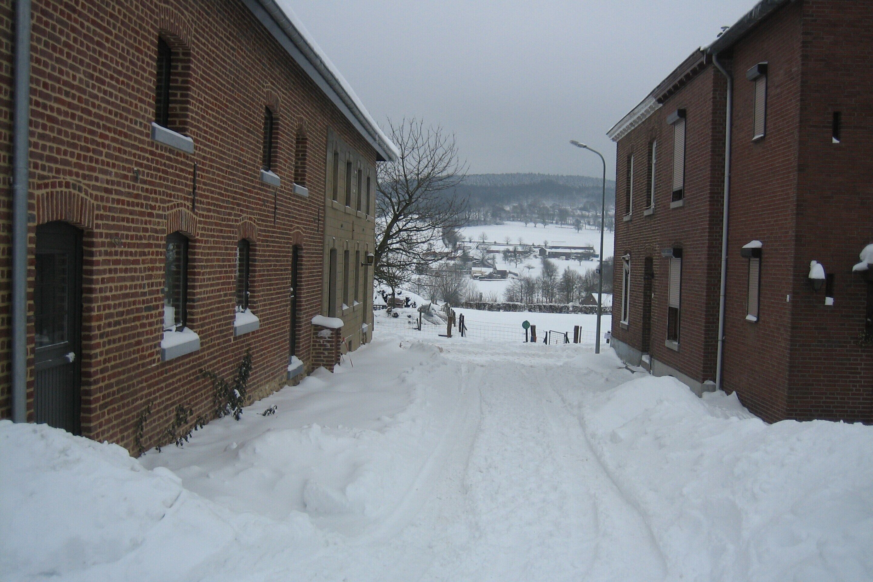 A snow-covered street with brick buildings on either side.