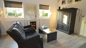 A living room with a sofa, a glass-top coffee table, a fireplace, and a cabinet.