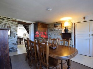 Cozy dining area with a round table and six chairs, featuring a wooden cabinet and a vase with flowers.