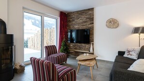 Een moderne woonkamer met een open haard, een televisie, een kerstboom en een bank.