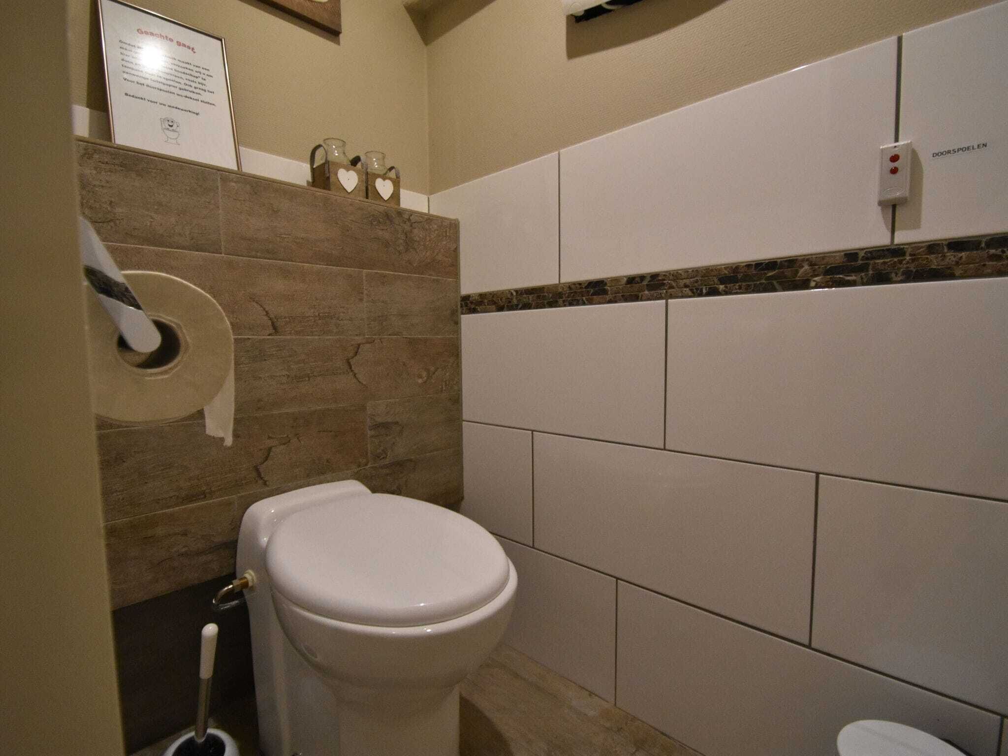 A bathroom with a toilet, a paper towel dispenser, and a hand dryer.