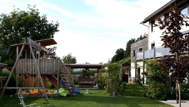 A playground with a wooden play structure, a slide, and a swing set. - Apartment in Heinrichskirchen (Roetz)