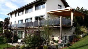 A two-story building with a balcony, outdoor seating, and a garden area. - Apartment in Heinrichskirchen (Roetz)