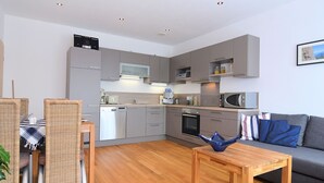 A compact living space with a kitchenette, dining area, and seating area. - Apartment in Heinrichskirchen (Roetz)