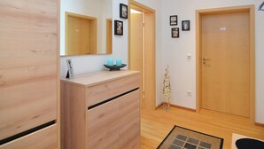 A modern hotel room with a wooden dresser, a large mirror, and a small table with candles. There are framed pictures on the wall and a door labeled "Entrance". - Apartment in Heinrichskirchen (Roetz)