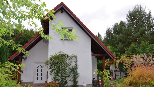 A white building with a red roof, surrounded by greenery and a paved area. - Waldblick Forest Retreat (Schmogrow)