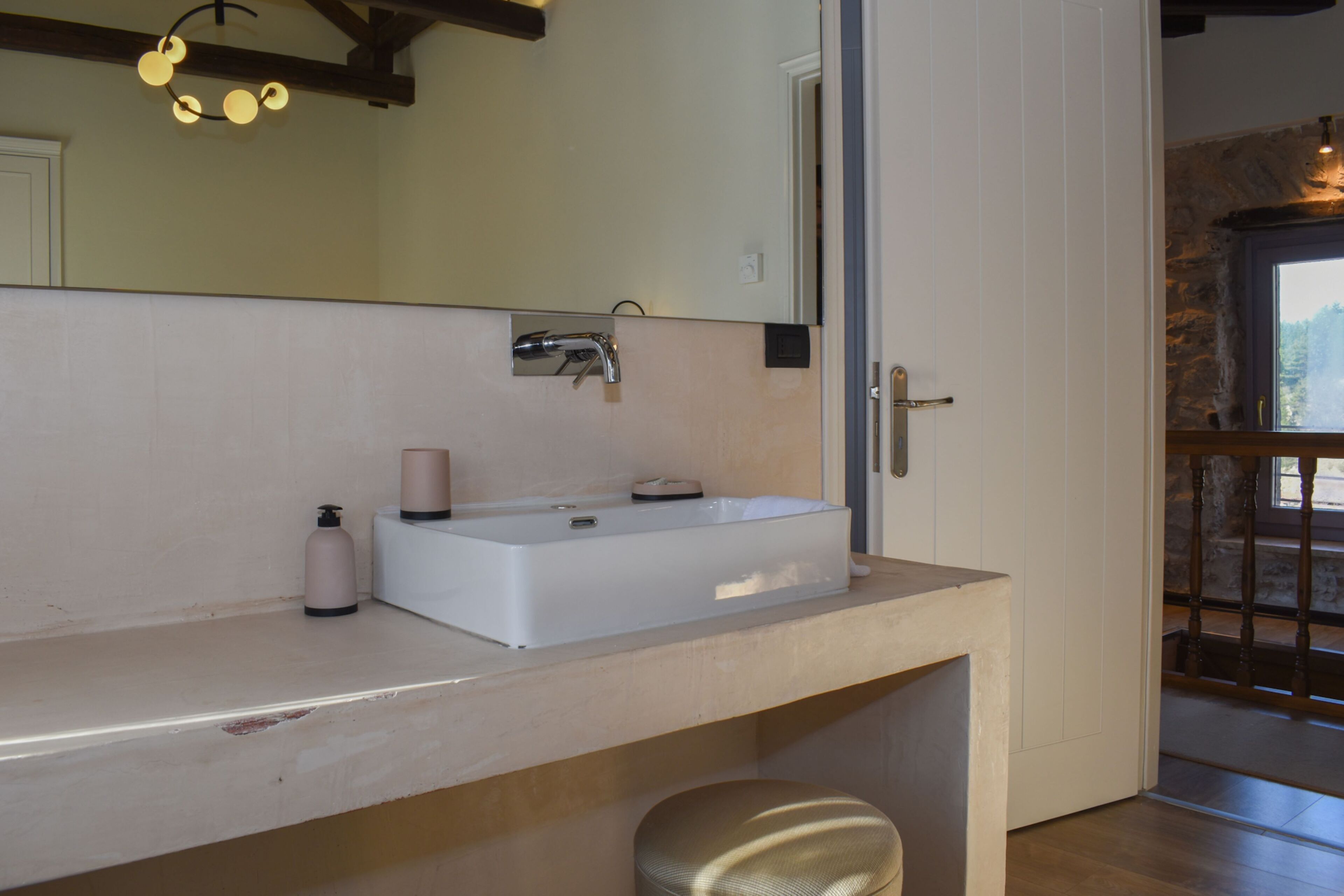 A bathroom with a white sink, a mirror, and a wooden door.