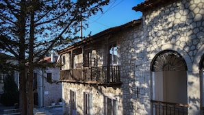 A stone building with a balcony, arched windows, and a stone facade. - Secluded Mountain Refuge - Theonimfi Paradise Gem (Gortynia)