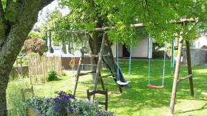 A playground with swings and a slide, surrounded by grass and trees. - Spacious Apartment in Pracht near Forest (Pracht)