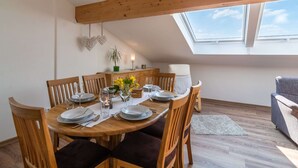 A dining area with a wooden table set for four, surrounded by chairs, a small plant, and a decorative heart on the wall. - Eifel Lakeside Family Escape (Ellscheid)