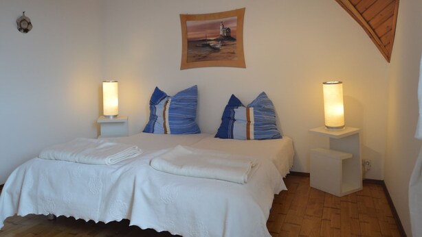 A bedroom with a wooden ceiling, a bed with white bedding, two bedside lamps, and a framed picture on the wall. - Farmstay Comfort in Juchen (Juechen)