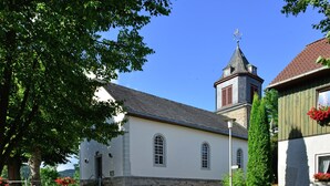A church with a clock tower, stone walls, and a cobblestone street. - Quaint Apartment in Eimelrod near Lake & Water Sports (Willingen)