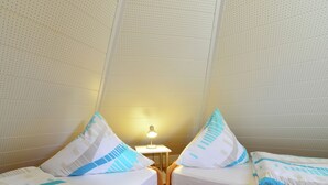 A room with two wooden beds, each with a white mattress and blue and white patterned pillows. There is a small table with a lamp between the beds. - Quaint Apartment in Eimelrod near Lake & Water Sports (Willingen)