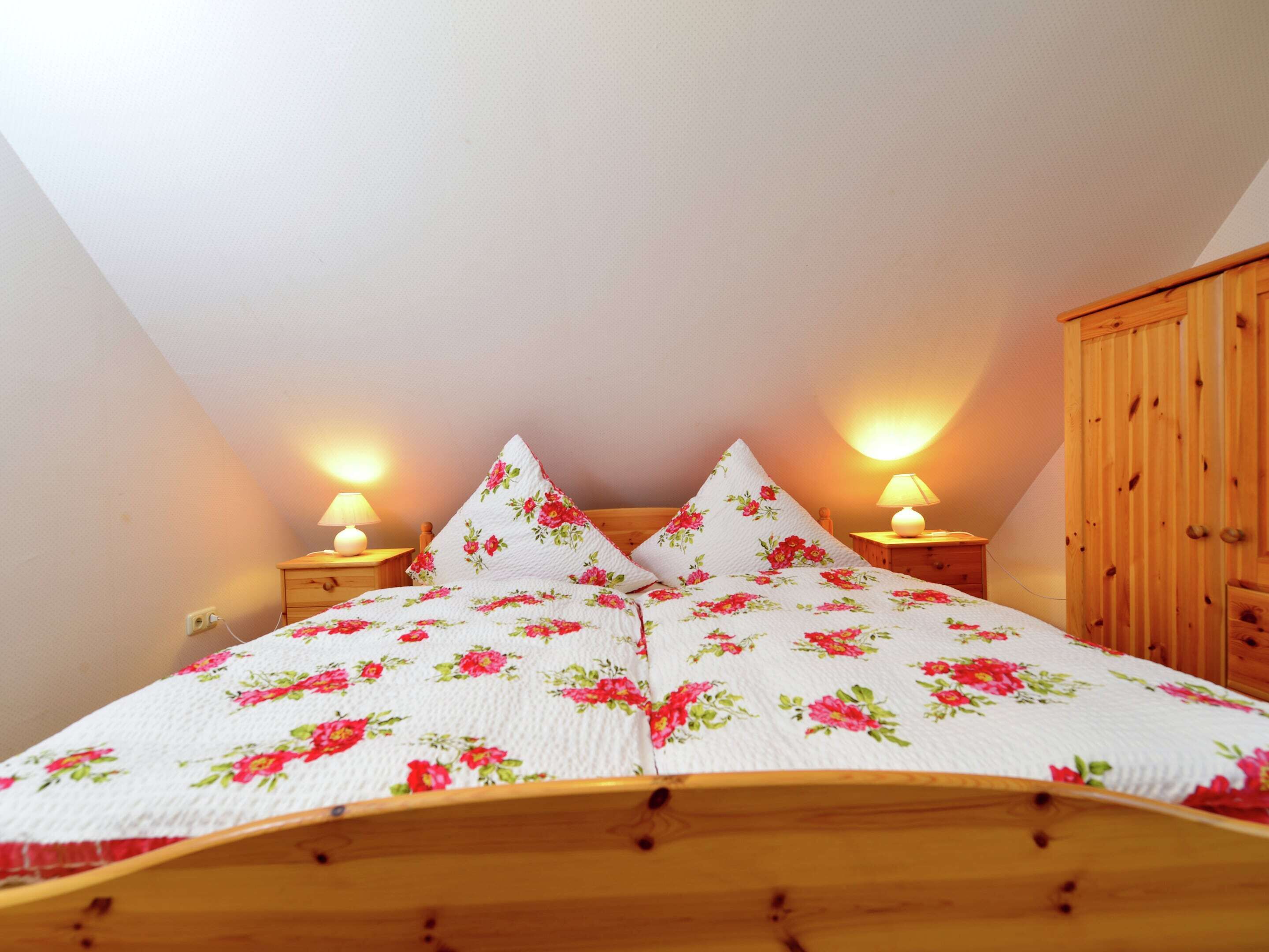 A bedroom with a wooden bed, two bedside lamps, and a wooden wardrobe.