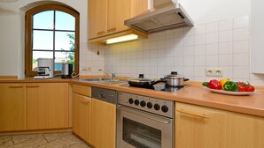 A modern kitchen with wooden cabinets, a stainless steel stove, and a sink. - Quaint Apartment in Eimelrod near Lake & Water Sports (Willingen)