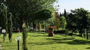 A well-maintained garden with a variety of plants and flowers, a clear pathway, and a yellow building in the background. - Farmhouse in Vinci With Pool & Vineyards (Vinci)