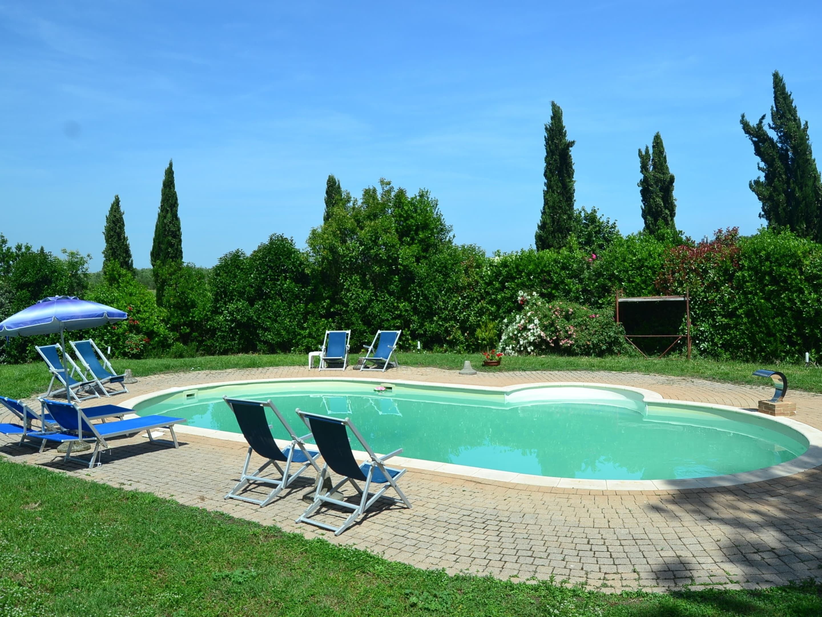 A swimming pool with lounge chairs and a blue umbrella.