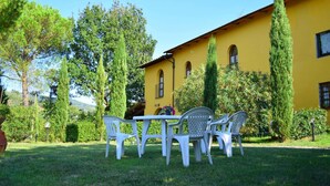 A yellow building with a garden patio featuring white plastic chairs and a table. - Farmhouse in Vinci With Pool & Vineyards (Vinci)