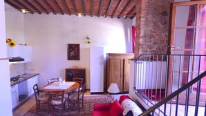 A cozy living area with a dining table, chairs, a red sofa, and a staircase with a railing. - Farmhouse in Vinci With Pool & Vineyards (Vinci)