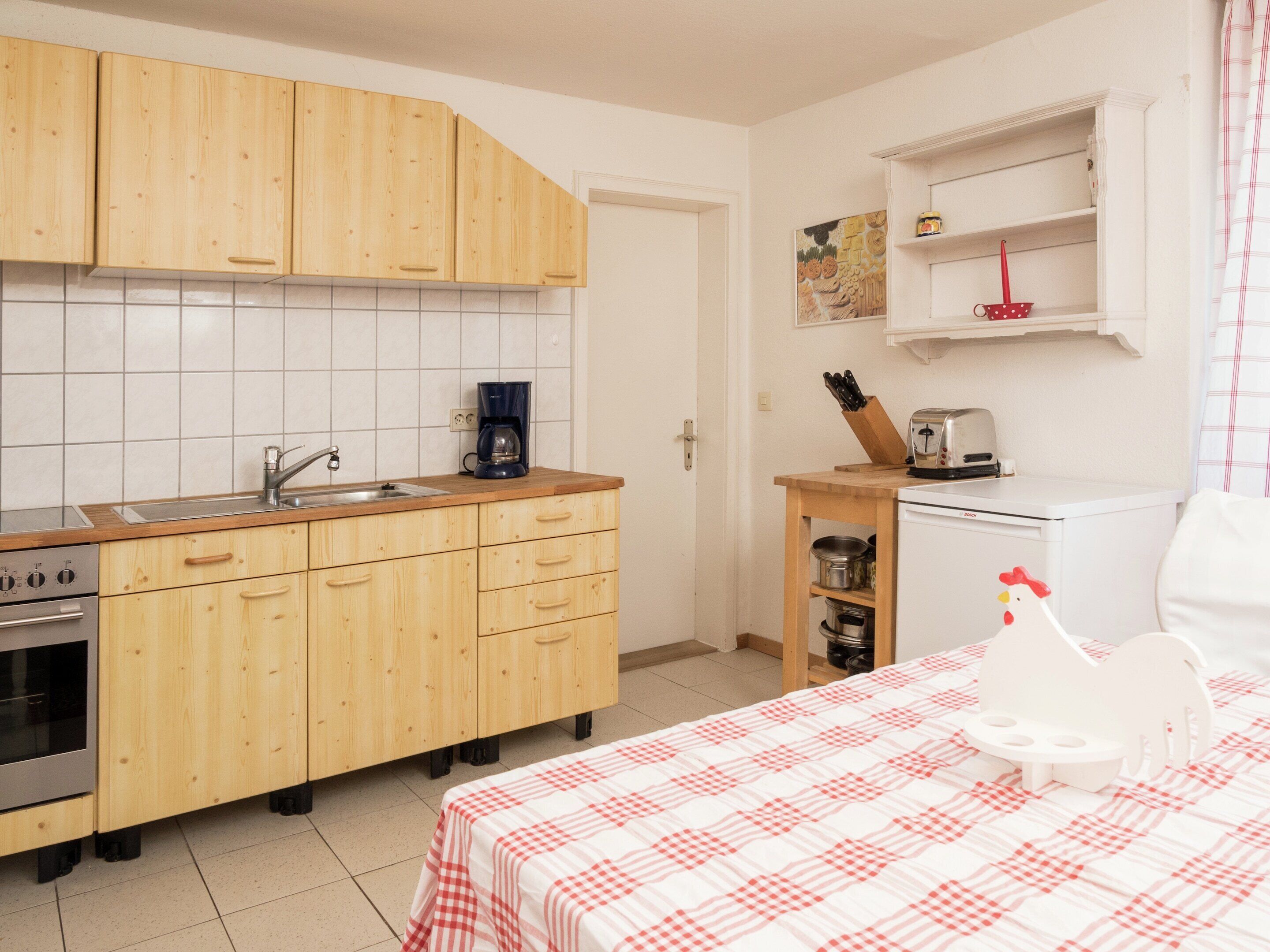 Una cucina compatta con mobili in legno, un lavello, una macchina da caffè, un tostapane e un piccolo frigorifero.