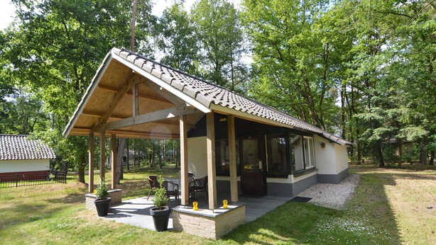 A covered outdoor area with a tiled roof, wooden beams, and a seating arrangement. - Detached Bungalow With Lovely Covered Terrace (Stramproy)
