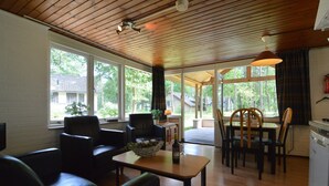 A spacious living area with a wooden ceiling, a dining table with chairs, and a television. - Detached Bungalow With Lovely Covered Terrace (Stramproy)