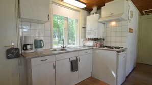 A compact kitchen with a sink, stove, and a window providing natural light. - Detached Bungalow With Lovely Covered Terrace (Stramproy)