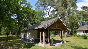 A small, single-story house with a sloped roof, a covered porch, and a brick foundation. - Detached Bungalow With Lovely Covered Terrace (Stramproy)