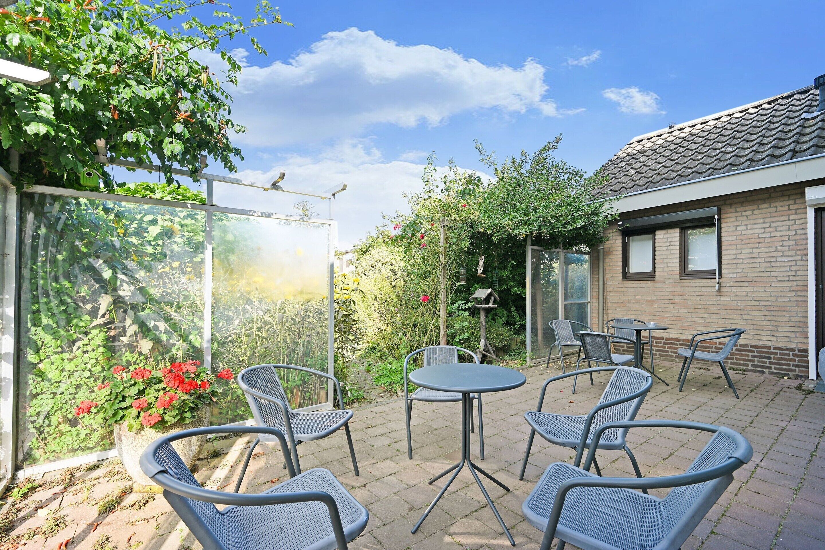 A patio with outdoor seating, a glass enclosure, and a brick building.