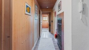 Un pasillo con paredes de madera, piso de baldosas y una puerta al final.