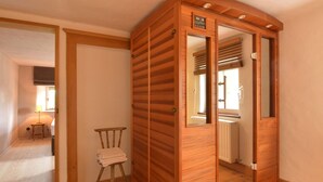A wooden room with a sliding door, a chair with a towel, and a lamp. - Holiday Home in Bullange With Sauna (Buellingen)