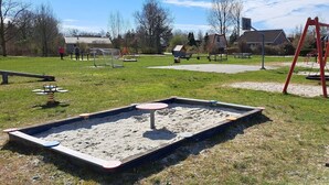 A playground with sandpit, swings, and benches.