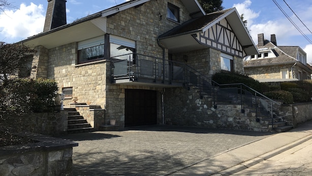 Una casa de piedra con un balcón, una escalera y una chimenea.