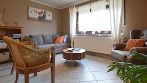 Una sala de estar con un sofá, dos sillones, una mesa de centro y una ventana con cortinas.