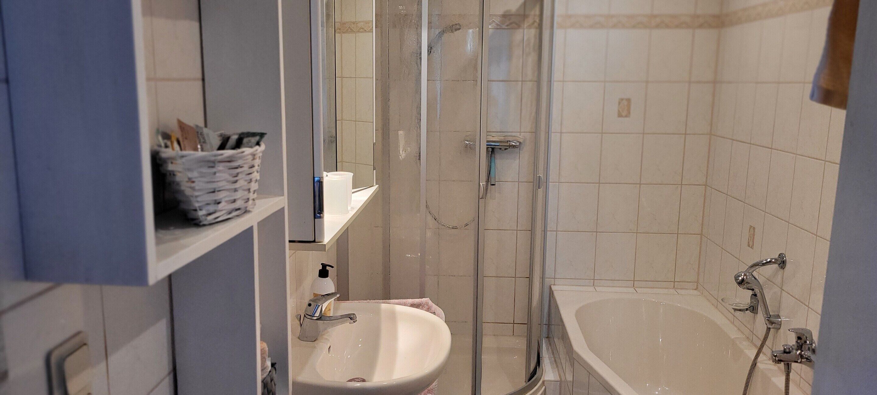 A bathroom with a sink, mirror, and shower.