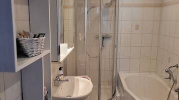 A bathroom with a sink, mirror, and shower.