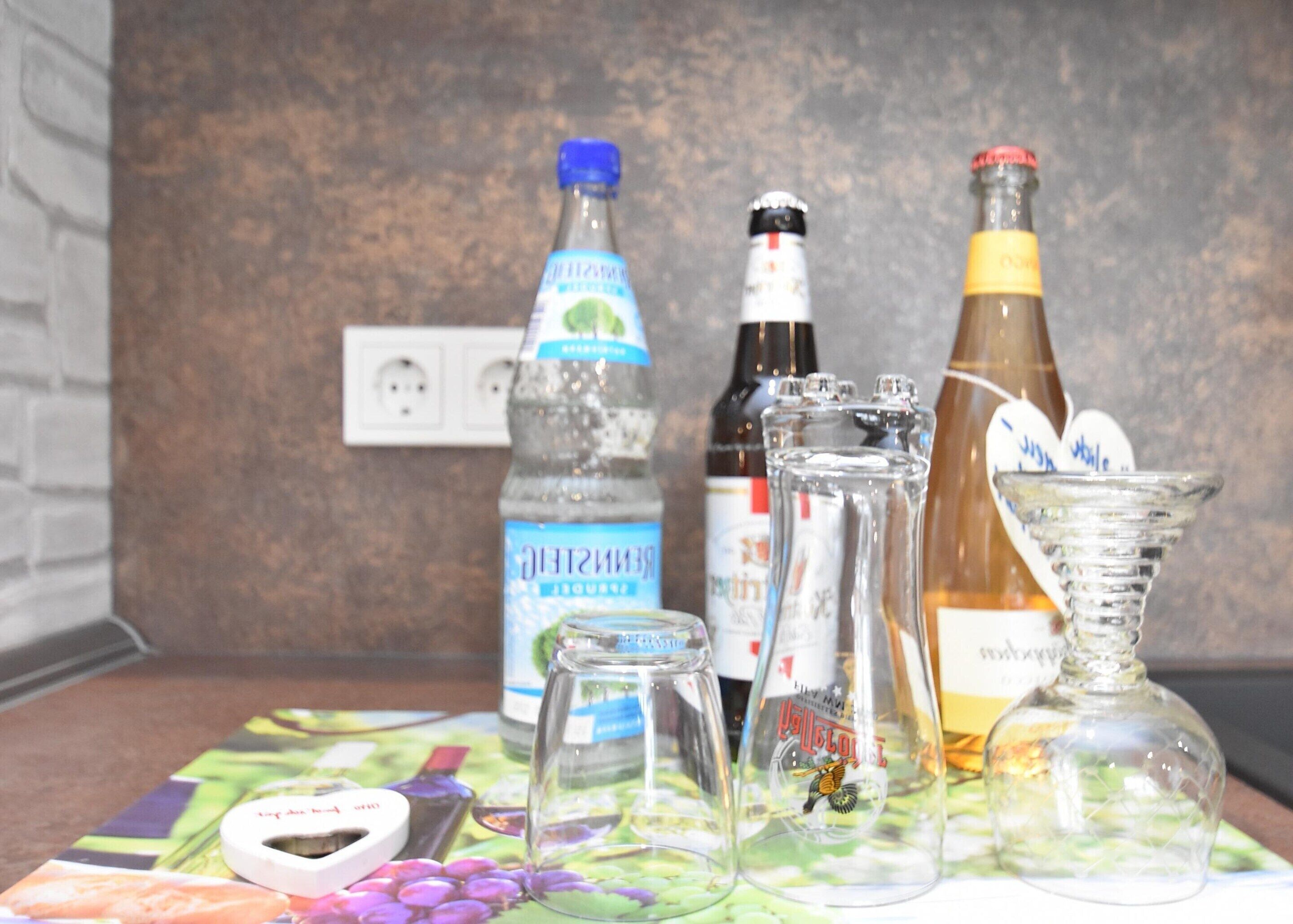 A table with various bottles and glassware, including a water bottle, a bottle of alcohol, and a decorative glass.