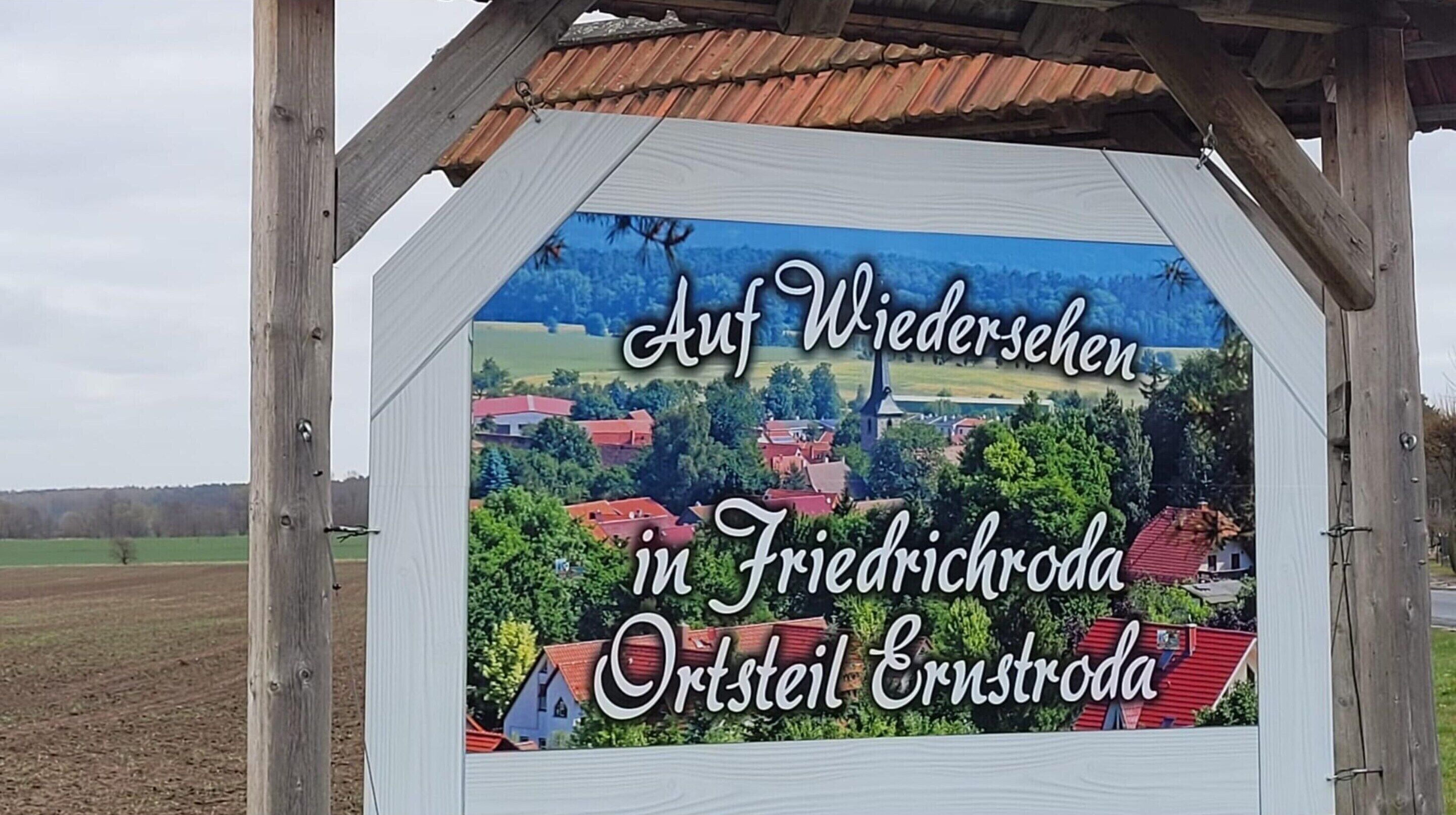Skilt med et naturskønt udsigt over en landsby, med huse og en kirke.