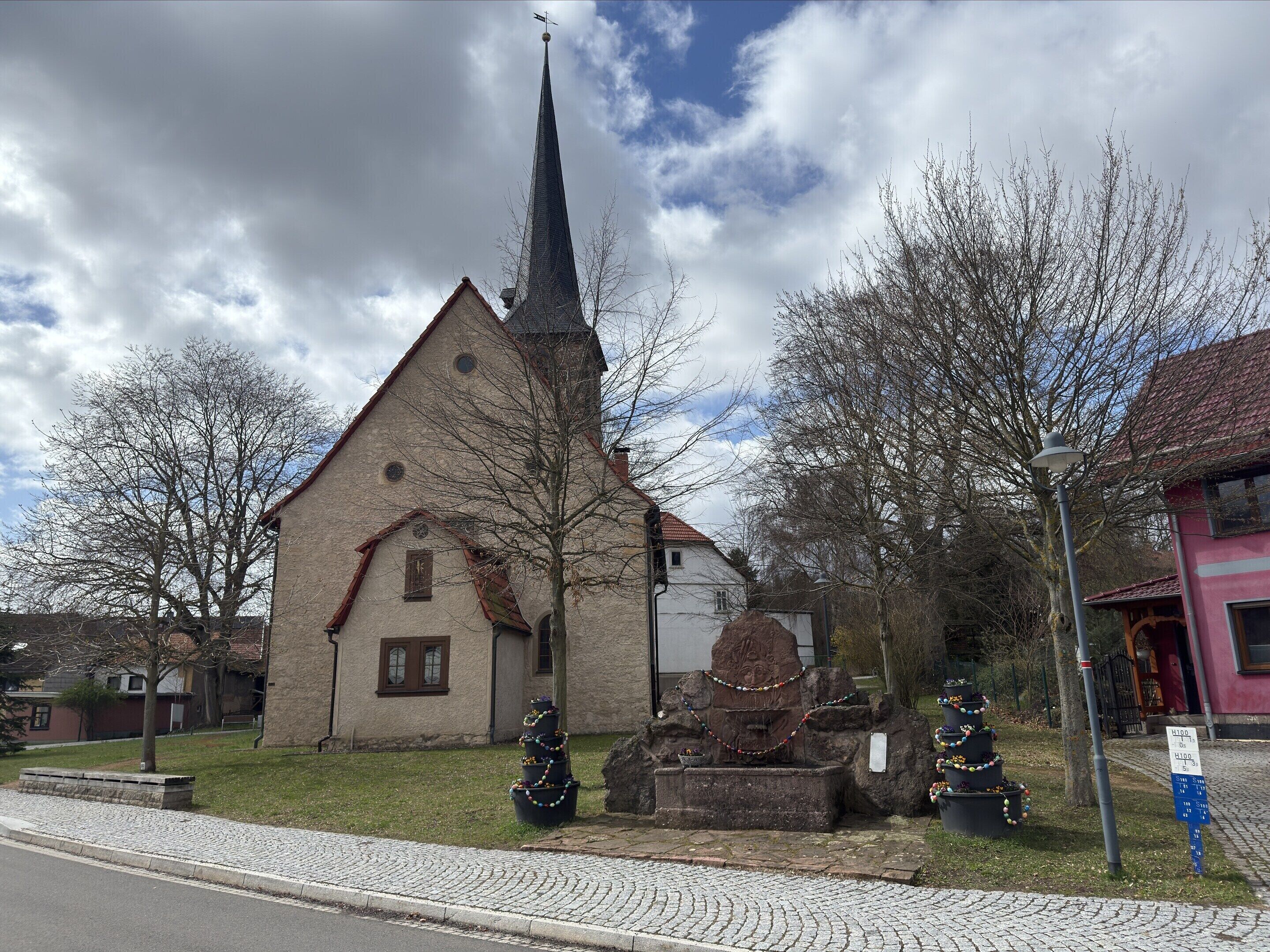 Eine Kirche mit einem hohen Kirchturm, einem Steinfountain und einem Weihnachtsbaum.