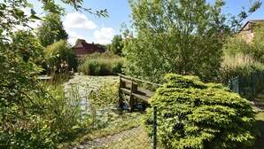 A serene garden with a pond, surrounded by lush greenery and a wooden bridge. - Cozy Apartment in Rerik near Beach (Rerik)