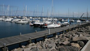 A marina with multiple boats docked, a wooden pier, and rocky shoreline. - Cozy Apartment in Rerik near Beach (Rerik)
