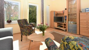 A living room with a sofa, armchair, TV stand, and a cabinet. - Cozy Apartment in Rerik near Beach (Rerik)