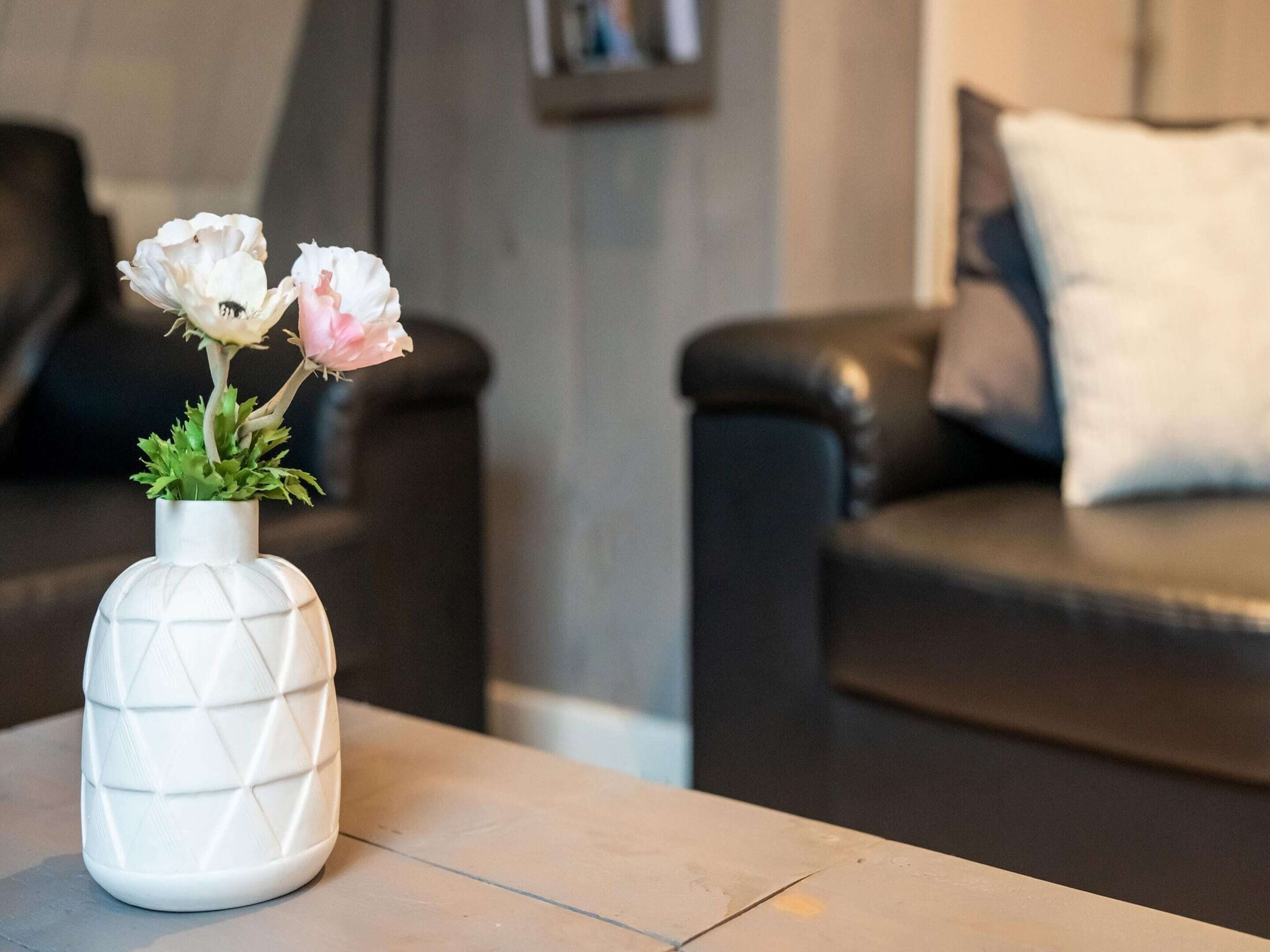 A white vase with a geometric pattern on a table in a living room.