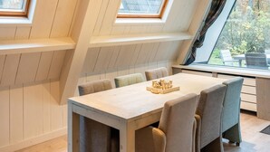 A dining area with a high ceiling and skylights, a wooden table, and six upholstered chairs. - Bungalow in Limburg Near Nature Reserves (Stramproy)