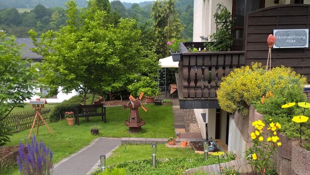A garden with a windmill, potted plants, and a wooden bench. - Holiday Home Niederehe Romantic Escape (Üxheim)